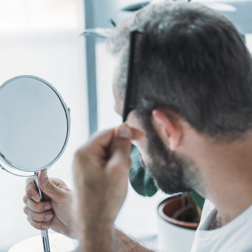 middle aged man combing hair and looking at mirror, hair loss concept middle aged man combing hair and looking at mirror, hair loss concept